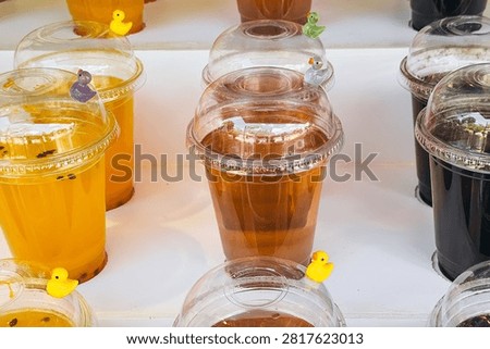 Clear plastic cups with drinks and small duck figures.