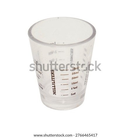 Clear plastic measuring cup for liquid ingredients. Small kitchen tool with milliliter and tablespoon markings for precise cooking and baking. Professional culinary measurement accessory.