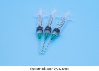 clear plastic syringes with needles isolated against a light blue background