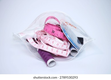 Clear pouch containing sewing essentials including tape measures and threads.