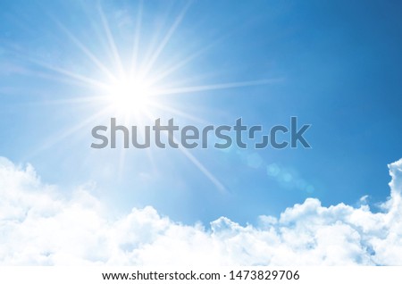 Clear sky with bright sun and rays in the atmosphere, below are light fluffy clouds