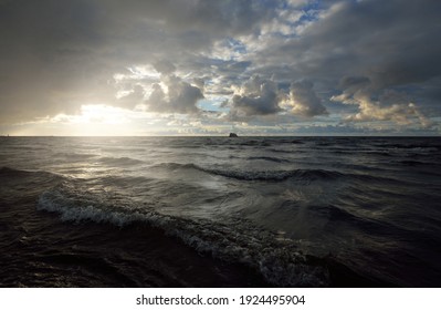 Clear sky with glowing cumulus clouds above the Baltic sea shore after thunderstorm at sunset. Dramatic cloudscape. Soft golden sunlight. Picturesque scenery. Fickle weather, nature, climate change