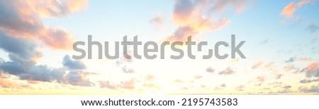 Clear sky with glowing pink cumulus clouds above the Baltic sea shore after thunderstorm at sunset. Dramatic cloudscape. Soft golden sunlight. Picturesque scenery. Fickle weather, nature, climate