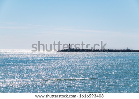 Clear sky over the sea with a breakwater and a lighthouse. Copy space background