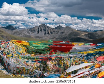 A clear sky with some clouds, the summit of Mila Mountain, with colorful flags hanging, in Lhasa, Tibet Autonomous Region, China.