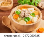 Clear soup with tofu and minced pork in wooden bowl on wooden table background. Asian Food