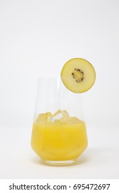 A Clear, Stemless Wine Glass With Organic Orange Juice And Ice.  A Slice Of Sun Gold Kiwifruit Is On The Rim Of The Glass