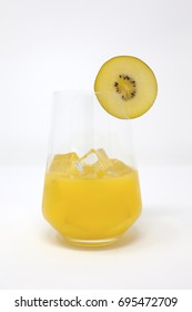 A Clear, Stemless Wine Glass With Organic Orange Juice And Ice.  A Slice Of Sun Gold Kiwifruit Is On The Rim Of The Glass