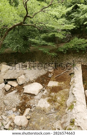 Clear stream flowing under an old stone bridge in a natural setting