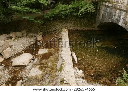 Clear stream flowing under an old stone bridge in a natural setting