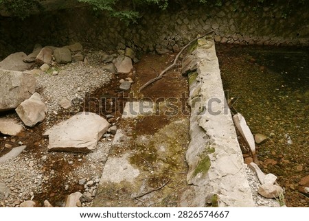 Clear stream flowing under an old stone bridge in a natural setting