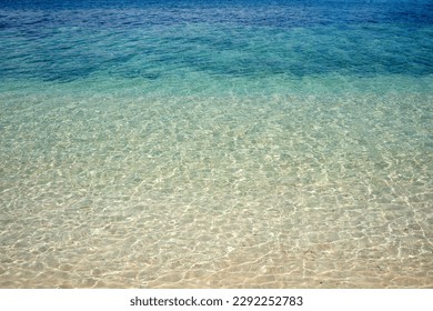 clear turquoise shallow water on white yellow tropical sand beach. Tropical background of paradise water with light reflections.