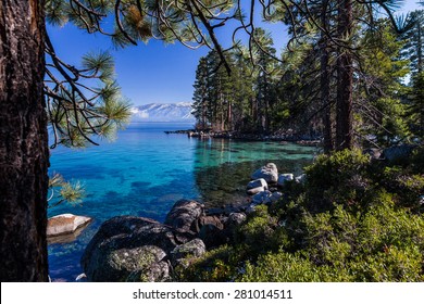 Clear, Turquoise Waters Of Lake Tahoe With Shoreline Of Pine Forest And Mountains
