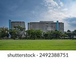 A clear view of Singapore HDB flat from afar showcasing straight grid line composition of colour housings of Singapore neighbourhood with clear blue sky in background and green grass field foreground