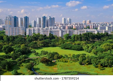 Clear view of skyline of high rise public housing on bright sunny day, with lush green public park in foreground. Beautiful day with blue sky and clouds, SIngapore