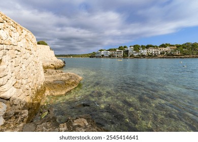 Clear water along rocky coastline with scattered clouds creating a calm vibe, porto petro, mallorca balearic islands, spain - Powered by Shutterstock