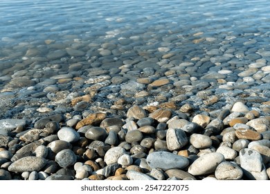 Clear water reveals smooth stones along the lakeshore on a sunny day in a tranquil natural setting - Powered by Shutterstock