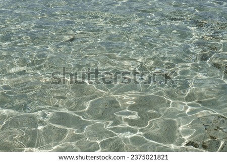 Clear water in shallow water. Glare on the water. Background with transparent water close-up.