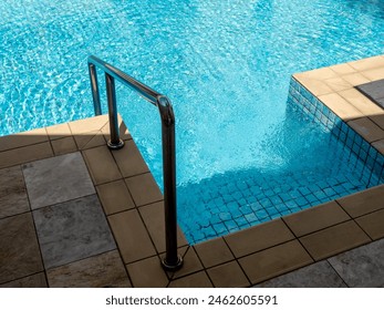 Clear water surface on swimming pool stair down steps with chrome metal grab bar with no body. Abstract pool texture, underwater pattern blue grid tiles, no people. Summer background concept. - Powered by Shutterstock