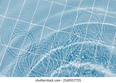 Clear water surface with ripple wave splashes and drops in swimming pool. Abstract turquoise or blue texture water wave and sunlight shadow reflections for background - Shutterstock ID 2169557725