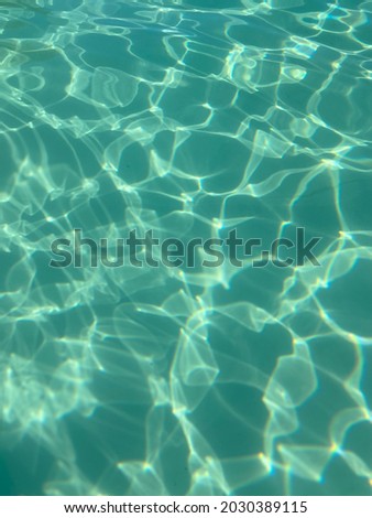 Clear water from a swimming pool - the white background of the pool floor and the sunlight make the water a greenish-blue, complemented by the reflections of the ripple of the water itself.