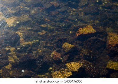 Clear Water From An Urban Storm Water Drain Pours Into The Leschenault Estuary , Bunbury, Western Australia  On A Late Afternoon In Winter With Rocks Submerged Underneath.