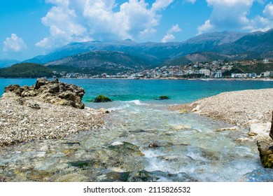 The clear waters of a mountain river close up flow into the Ionian Sea on the beautiful pebble Potam beach. Himare town. Albania. Summer cloud landscape.