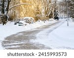 Cleared from snow sidewalk in winter park. Clean walkway in snowy park. Winter sunny day, cleared pedestrian road in city park after snow storm, snow removal work in the city. Selective focus