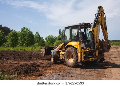 Clearing and leveling a private land plot. Yellow excavator driven earth in a wide bucket, back view - Shutterstock ID 1762290533