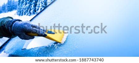 Clearing and remove snow from windshield, Scraping ice. Winter season car window cleaning. Copy space for your text. Panoramatic banner.