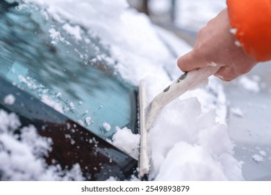 Clearing snow from a car windshield on a winter morning in a suburban area - Powered by Shutterstock