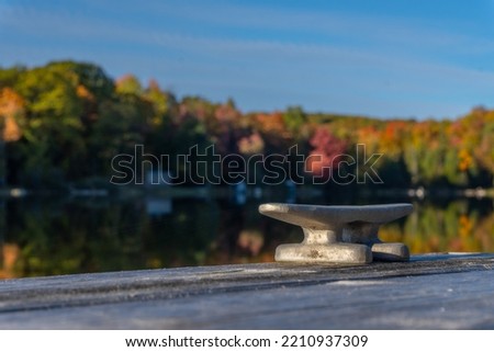 A cleat on dock waits for a boat to tie up on this small lake.