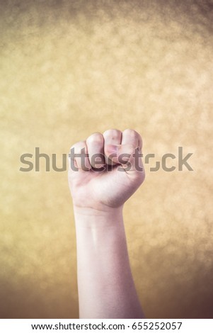 A clenched fist on the gold background.
