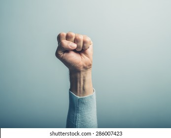 A clenched male fist is up in the air - Shutterstock ID 286007423