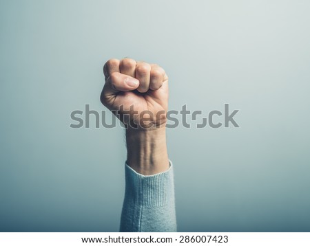 A clenched male fist is up in the air