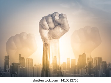 A clenched male fist is up in the air on city sunset background, fighting, competition, revolution, people determination concept. Double exposure affect 