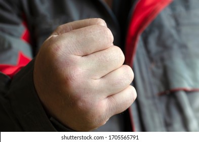 A clenched male fist. A man in work clothes shows his fist to the camera. Eye level shooting. Selective focus. Close-up. - Powered by Shutterstock