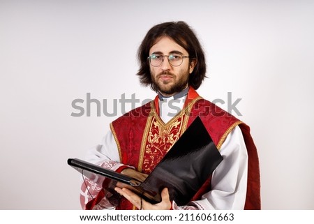 The clergyman poses with a document case. He looks at the camera.