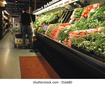 Clerk Works In Produce Section Of Grocery Store.