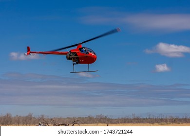 Clermont, Queensland, Australia - 04/28/2020; A Small Red Helicopter Being Used To Muster And Roundup Cattle In The Queensland Outback.