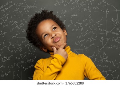 Clever black child thinking on chalkboard background with science formulas