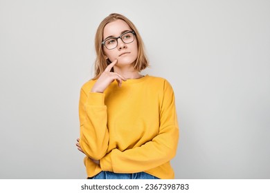 Clever blond student girl with glasses touch chin thinks, chooses isolated on white studio background with copy space. Confidence smart genius