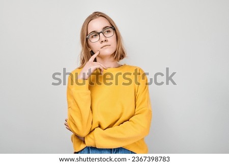 Clever blond student girl with glasses touch chin thinks, chooses isolated on white studio background with copy space. Confidence smart genius