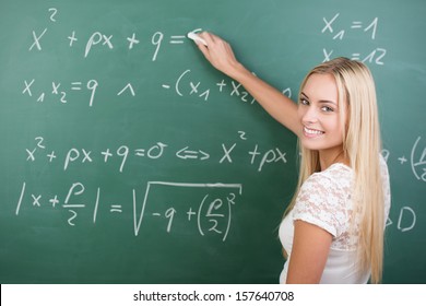 Clever confident female student in the classroom writing on a chalkboard completing mathematical equations - Powered by Shutterstock