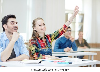 Clever Girl Raising Hand At Lesson With Groupmate Near By