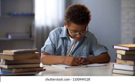 Clever male pupil doing math homework, solving equation in notebook, knowledge