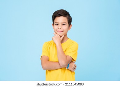 Clever mixed race boy in yellow t shirt rubbing chin and looking at camera while thinking against blue background - Shutterstock ID 2111545088
