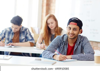 Clever Teenage Learner Sitting By Desk During Exam And Carrying Out Written Task Or Writing Essay