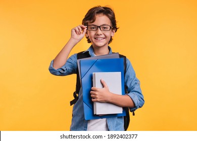 Clever young boy holding folders for studing at school isolated over yellow background - Shutterstock ID 1892402377