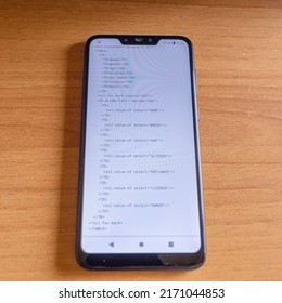 click of xml code visible on the smartphone screen, resting on the desk